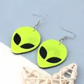 Close-up of fluorescent green acrylic alien earrings with silver metal hooks on blue decor - Yellow