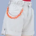Detail of neon orange acrylic chain and silver ball chain on denim shorts waist - Orange