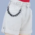 Detail of chunky black acrylic chain and silver bead chain on white denim shorts - Black