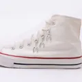 Macro detail of silver horseshoe shoe charms with Good Luck engraving on white canvas boots - Lucky Horseshoe