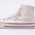 Three silver dollar sign charms with lobster clasps attached to white canvas sneakers - Dollar Sign
