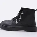 Detalle de botas militares negras mate con colgantes de espada gótica plateada en ojales - Colgante de Cruz de Clavo