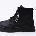 Detail of silver heart-shaped charms and metal eyelets on black leather Martin boots - Hollow Heart