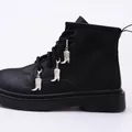 Close-up of silver metal boot charms with scroll relief on black lace-up Martin boots - Cowboy Boot