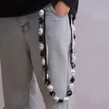 Cadena para pantalón con cuentas Grad en blanco y negro y lazo sobre jeans claros - Cadena Pantalones Cuentas Blanco y Negro con Cinta