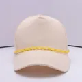 Detailansicht einer beigen Canvas-Baseballkappe mit einer dekorativen gelben Kunststoffkette - Gelb