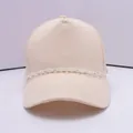 Detail einer beigen Baumwoll-Basecap mit einer dekorativen weißen Kunststoff-Gliederkette - Weiß