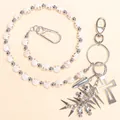 Punk broekketting met witte schedelkralen, kruishanger en metalen spikes op beige achtergrond - Enkellaagse Witte Schedel Kralen Broekketting