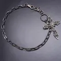 Detalle de cadena de metal oscuro con un colgante de cruz adornado con pedrería - Estilo Cruz con Strass / Color gunmetal