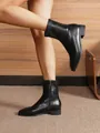 Close-up of black matte leather ankle boots with side zipper and square toe on a model - EU 35 / Black