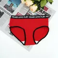 Detailed close-up of red ribbed cotton panties with black slogan waistband and floral background - S / Red
