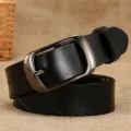 Cintura classica in vera pelle nera con fibbia in metallo opaco su sfondo rustico - Nero