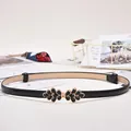 Women's black patent leather skinny belt with a gold-tone rhinestone floral buckle - Enamel Petal Buckle / Black