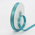 Lake blue satin ribbon with gold glitter finish on a white spool for gift wrapping - Teal