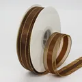 Deep brown 2.5cm chiffon ribbon with gold metallic edges on a white spool roll - Coffee