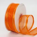 Vibrant orange organza ribbon with gold metallic edges on a white spool for DIY crafts - Orange