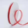 Red chiffon ribbon with gold metallic edges on a white spool for gift wrapping - Red