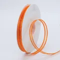 Orange organza ribbon with gold trim on white spool for DIY crafts and gift wrapping - Orange
