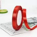 Red satin ribbon with gold metallic edges on a roll for elegant gift packaging and DIY crafts - Red