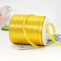 Bright yellow decorative ribbon with gold glitter stripes on a white spool for gifts - Gold-edged Golden