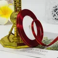 Deep red satin ribbon with gold trim edge on spool for elegant gift wrapping - Burgundy
