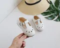 Detail view of white T-strap Mary Jane baby shoes with hollow-out patterns and metal buckle - 16 / White