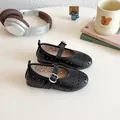Detail of girls black Mary Jane shoes with laser-cut patterns on a white table - 23-26 / Black