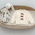 Detail der cremeweißen Baby-Strickjacke mit roten Samtschleifen und 3D-Punkttextur - 73cm / Aprikose (Strickjacke)
