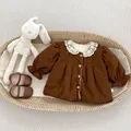 Detail of brown corduroy baby coat featuring a lace collar and elastic ruffles - 73cm / Brown