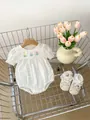 Close-up of white lace baby bodysuit featuring floral tulip embroidery and ruffles - Size 66 / Baby Romper