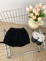 Detail of black ruffled toddler shorts with elastic waist on a metal background - Pants / 66cm