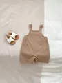 Close-up of cotton baby romper with front pocket and button details on a soft fabric base - 66CM / Brown