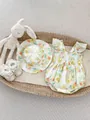Flat lay of floral baby bodysuit with matching sun hat and lace shoes in a woven basket - White / 66cm