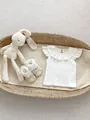 Flat lay of baby flutter sleeve top with ruffled collar and lace shoes in a basket - 66 / White
