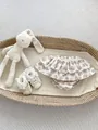 Detailed view of floral ruffle baby bloomers and lace newborn shoes in a cozy basket - 73