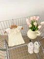 Detalle de top sin mangas con volantes para bebé y zapatos de encaje en una cesta - Amarillo / 66CM