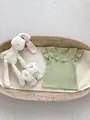 Detail of baby ruffled top in bean green ribbed knit with lace shoes and a plush bunny - 66 / Green