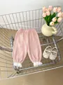 Detail of pink cotton crepe baby trousers featuring white lace ruffled hems in soft lighting - 66cm / Bottoms / Pink