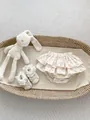 Close-up of floral ruffle baby bloomers and matching lace infant shoes in a basket - 73