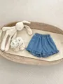 Détail du short en jean pour bébé avec volants et taille élastique dans un berceau - Short en Jean à Volants / Bleu / 73cm