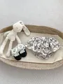 Detailed view of floral ruffle baby bloomers and lace bow shoes on a textured rug - 73 / Black White Style (Bloomers/Shoes/Doll)