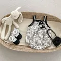 Close-up of baby girl floral romper with black bows and lace shoes in a basket - Baby Romper / 66cm