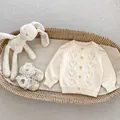 Detail van crème gebreid babyvest met ruitpatroon en zachte schoentjes met kant - 66cm / Rijstabrikoos Cardigan