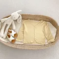 Flat lay of baby ginger knit cardigan and white sandals with a plush bunny toy - 66 / Yellow