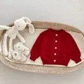 Detail van rood gebreid babyvest met ruitpatronen en lichte ronde knopen - 66cm / Rode blazer