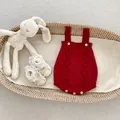 Detail van rode gebreide baby romper met hartpatronen en gele ronde knopen - 66cm / Rode Kruippakje