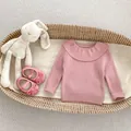 Detail of baby girl pink ribbed knit sweater with large ruffled collar in a soft basket - 66 / Tops / Pink