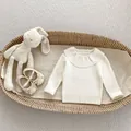 Detailed view of baby white ribbed knit sweater with ruffle collar and bow shoes in a basket - Off-white / 73