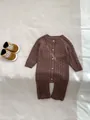 Nahaufnahme von Zopfstrickmuster und Holzknöpfen am braunen Baby-Strickstrampler - 66cm / Set / Braun