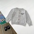 Detailed macro view of light gray knit cardigan with embroidery and wooden buttons - 73cm / Gray